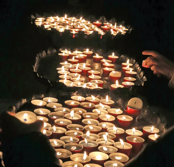 Jovem mão fiel acende uma vela — Fotografia de Stock