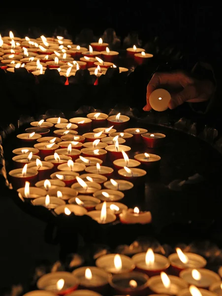 Oudere vrouw in gebed en stak een kaars in de kerk — Stockfoto