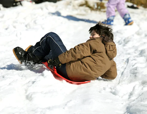 Хлопець грає з упряжках на снігу — стокове фото