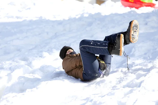 Kind spielt mit Schlitten auf Schnee — Stockfoto