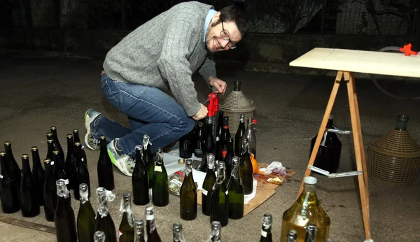 Homme verser du vin du demijohn dans des bouteilles en verre — Photo