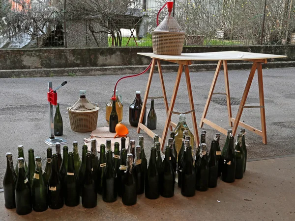 Pour red wine from the demijohn to bottles — Stock Photo, Image