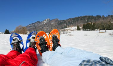 couple with blue and orange snowshoes in the mountains clipart