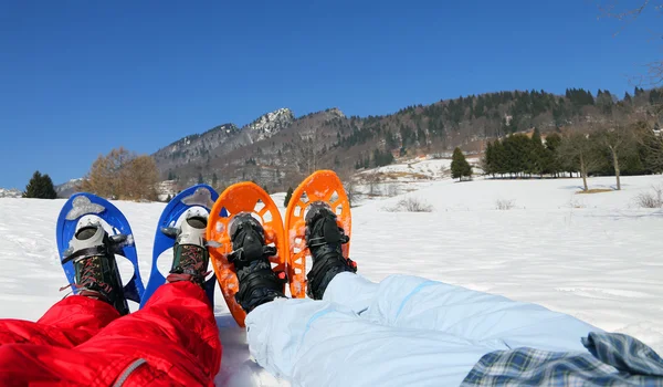 Coppia con ciaspole blu e arancioni in montagna — Foto Stock