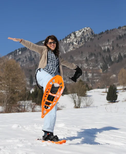 Beautiful woman with snowshoes in snowy mountain — Zdjęcie stockowe