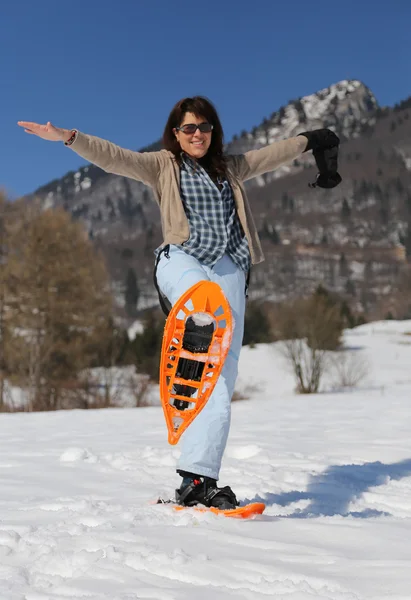 Pretty woman with snowshoes in snowy mountain — Stockfoto