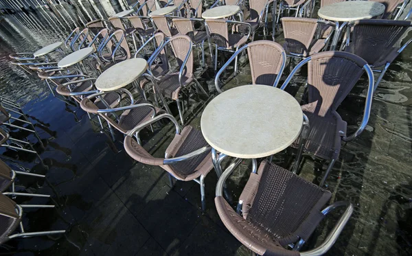 Muchas sillas de los cafés al aire libre con agua en marea alta — Foto de Stock