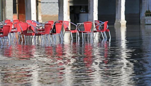 Cadeiras dos cafés ao ar livre com água na maré alta — Fotografia de Stock