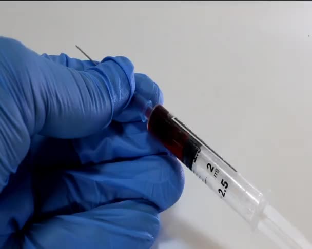 Doctor with glove and the syringe with blood sample — Stock Video