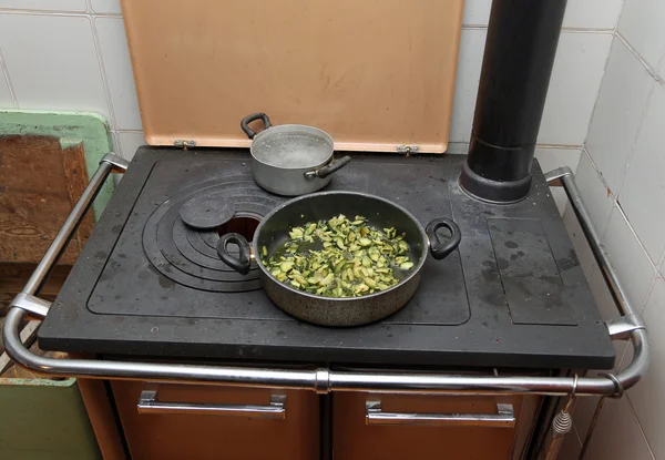 Pot with cooked zucchini in the ancient stove with fire lit — Stock Photo, Image