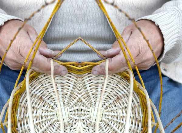 Elderly craftsman creates a woven wicker basket — Stock Photo, Image