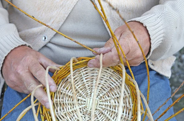 Hände älterer Handwerker schaffen einen geflochtenen Weidenkorb — Stockfoto