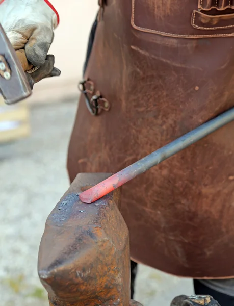 Schlosser liefert das weiß glühende Eisen mit dem Hammer auf den Amboss — Stockfoto