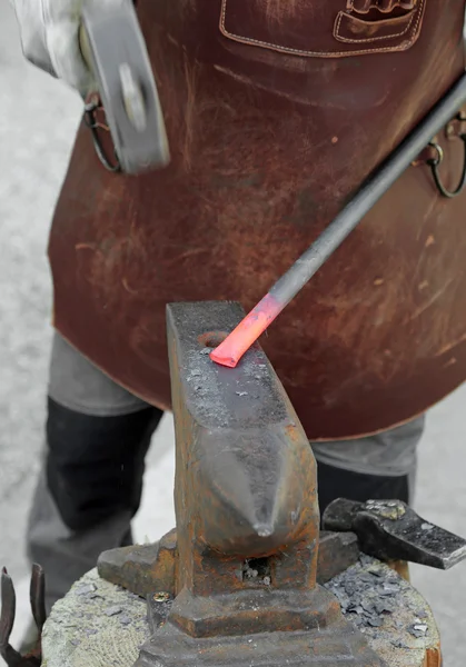 Fachkundiger Schlosser liefert das weiß glühende Eisen mit einem Hammer auf die — Stockfoto