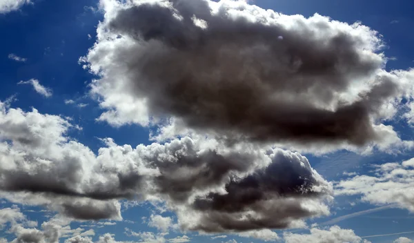 Zářivě černé a bílé mraky v modré jasno — Stock fotografie