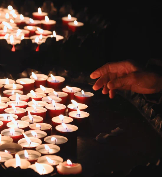 Hand van een oudere vrouw verlichting een kaars te bidden — Stockfoto