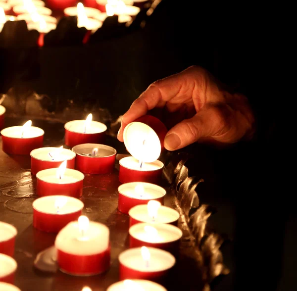 Hand van een oudere vrouw verlichting een kaars te bidden — Stockfoto