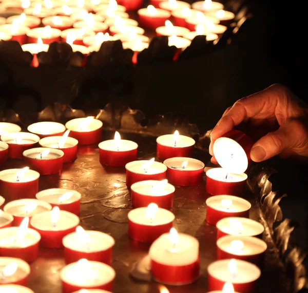 Oudere vrouw verlichting een kaars te bidden tijdens de mis — Stockfoto