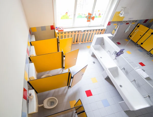 Kindergarten bathroom with washbasins and cabins without childre — Stock Photo, Image