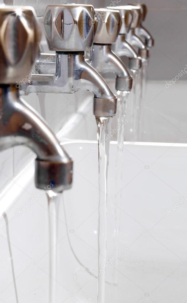 steel taps with drinking water flowing in college bathroom