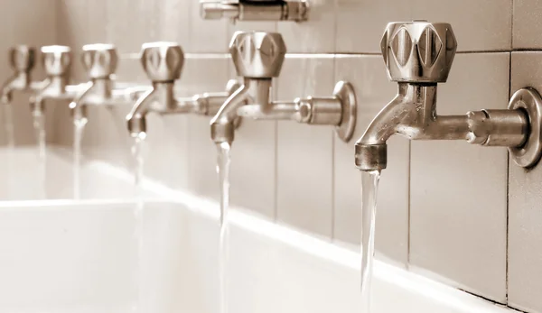 Fila de grifos de acero en un baño grande en la comunidad — Foto de Stock