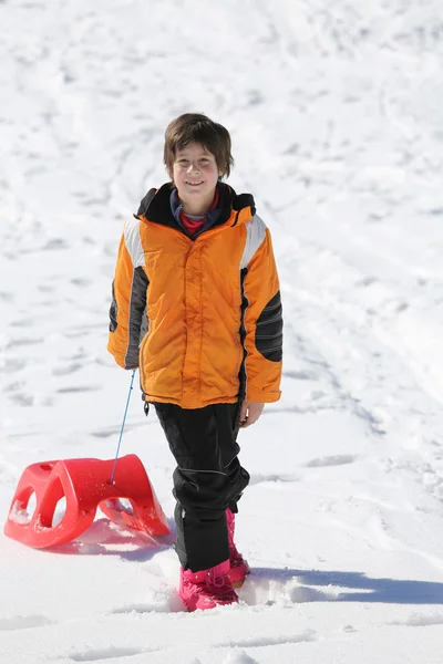 Young boy having fun on the red sleigh in the mountains — Stock Photo, Image