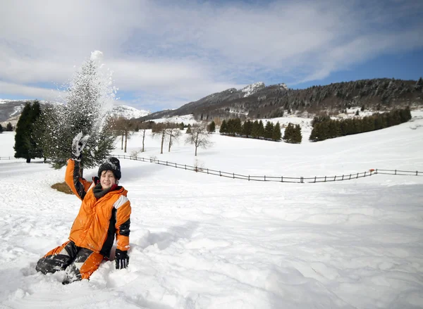 Menino brincar com a neve nas montanhas no inverno — Fotografia de Stock