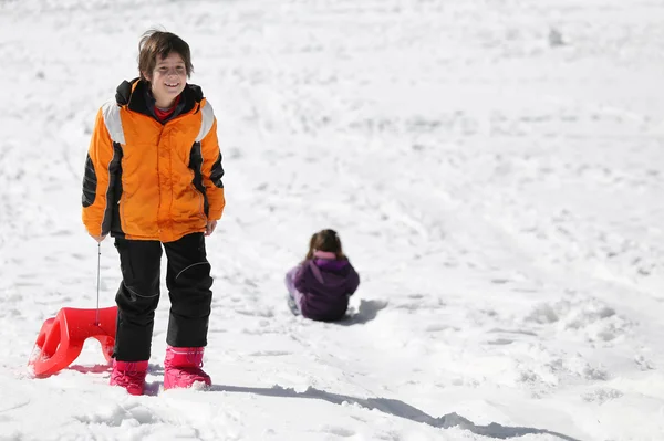 Niño divirtiéndose en el trineo rojo en las montañas en invierno —  Fotos de Stock