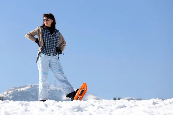 Vacker kvinna med snöskor i bergen på vintern — Stockfoto