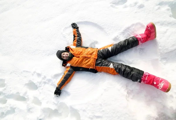 Niño crea el contorno de un ángel en la nieve — Foto de Stock