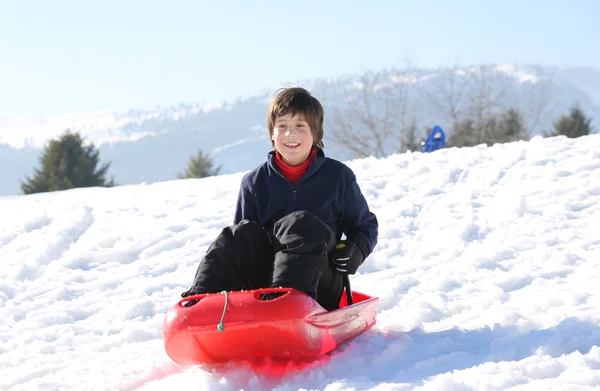 Niño con el pelo castaño en el invierno juega con Bob en la montaña —  Fotos de Stock