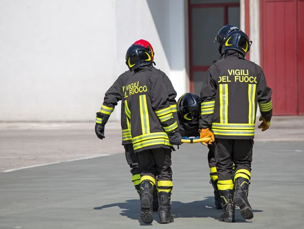 Cuatro valientes bomberos llevan a un compañero bombero —  Fotos de Stock