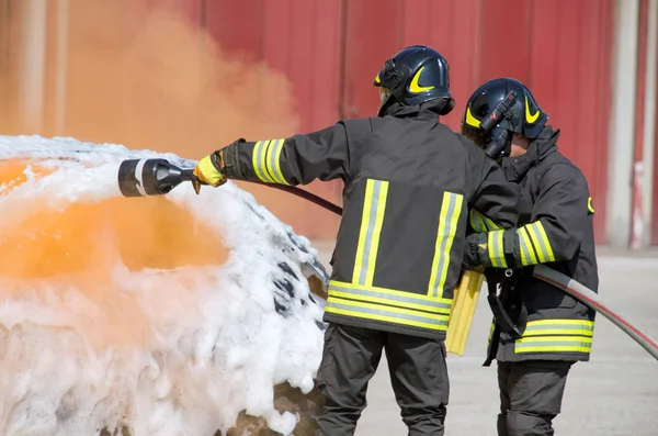 Två brandmän i aktion med skum — Stockfoto