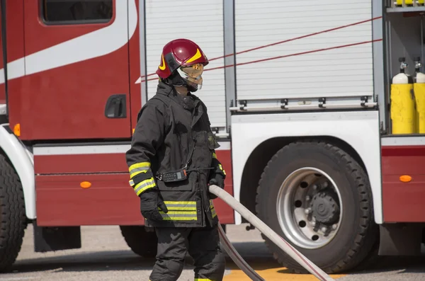 Brandmän med slangen att släcka bränder och firetruc — Stockfoto