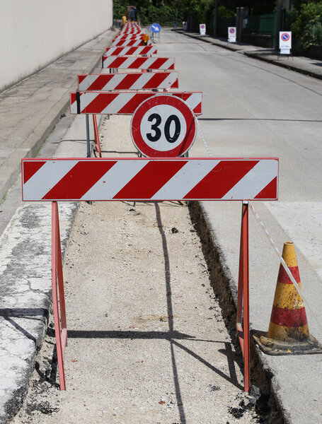 speed limit sign and hurdles in the road excavation