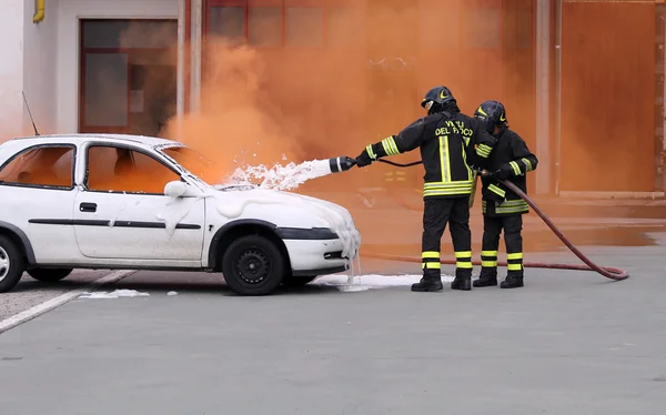 Bomberos durante el ejercicio para apagar un incendio en un coche — Foto de Stock