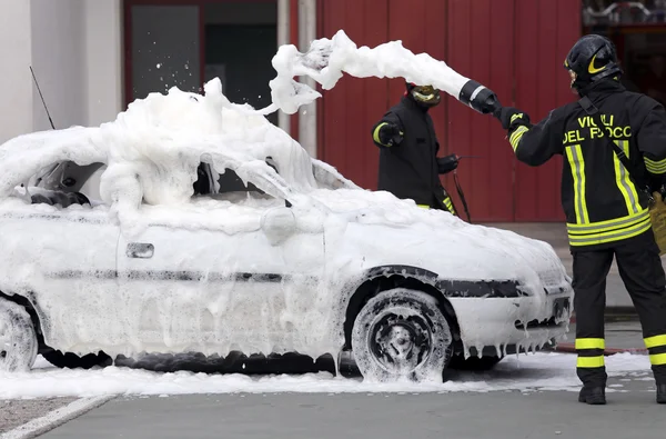 Bomberos durante el ejercicio para apagar un incendio en un coche —  Fotos de Stock