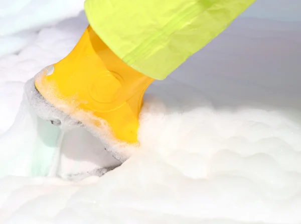 Yellow boots into the foam pollutant — Stock Photo, Image