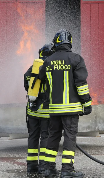 Brandweerlieden met zuurstofflessen uit het vuur tijdens een training — Stockfoto