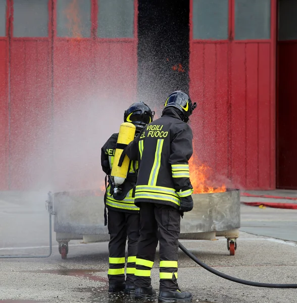 Brandweerlieden met zuurstofflessen uit het vuur tijdens een training — Stockfoto