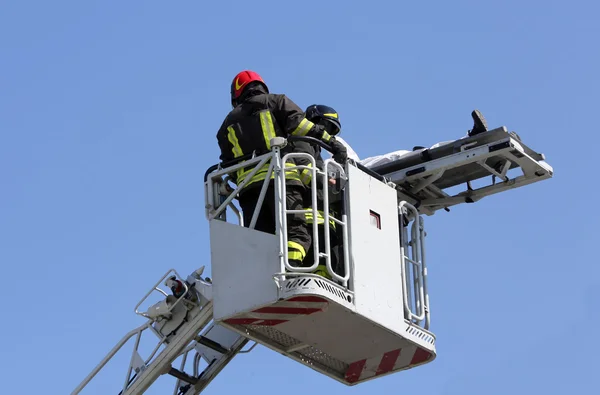 Corajosos bombeiros na gaiola do caminhão de bombeiros com a maca — Fotografia de Stock