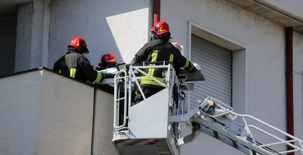 Bombeiros na gaiola do caminhão de bombeiros salvar a pessoa ferida — Fotografia de Stock