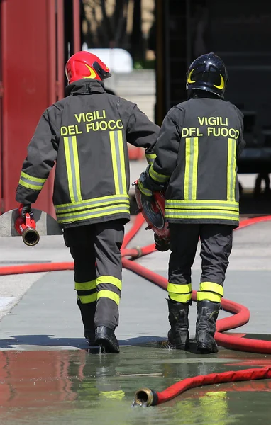 Firefighters carry the hydrant and hose pipes after put off the — Stock Photo, Image