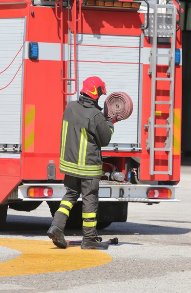 Пожарный поднял красный шланг после того, как отложил пожар. — стоковое фото
