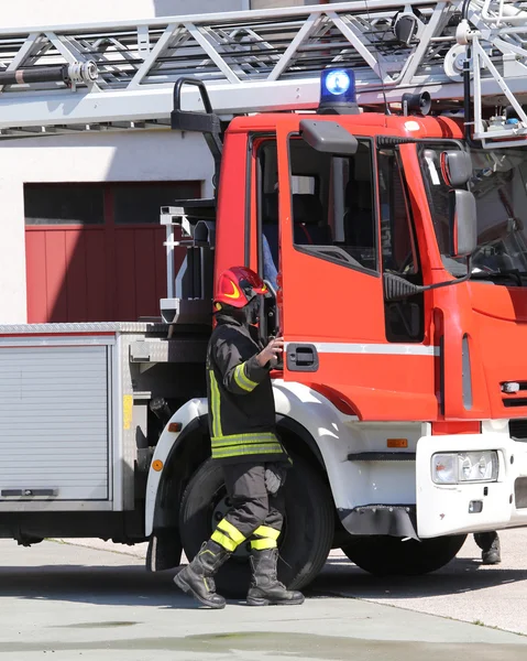 Fireman and a firetruck in the barracks of the fire brigade — Stock Photo, Image