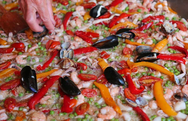 Mão do chef acrescenta um pouco de salsa em paella arroz — Fotografia de Stock