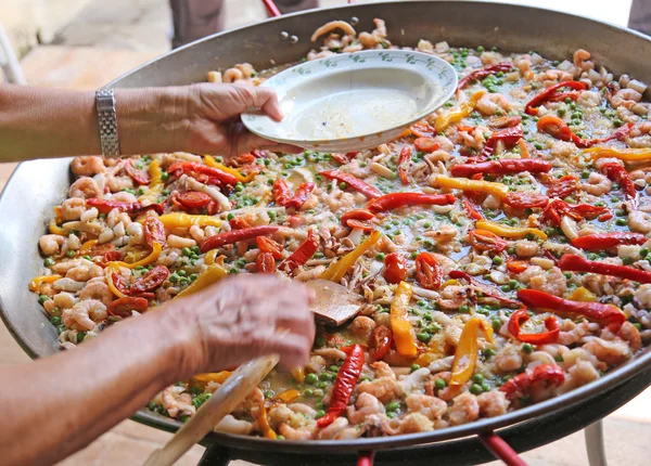 Mano del chef añade camarones en la paella de arroz con mariscos — Foto de Stock