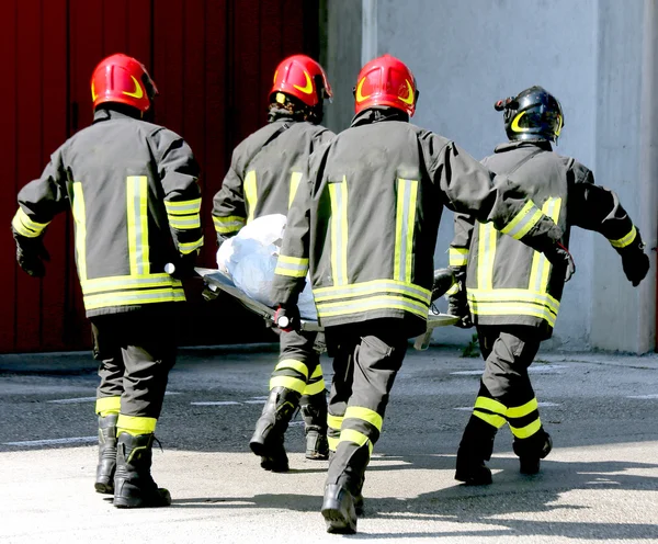 Four firemen in action carry a stretcher — Stock Photo, Image
