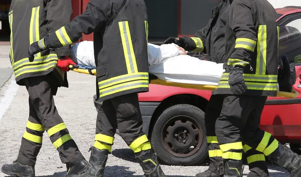 Quatre pompiers en action portent une civière avec blessés — Photo