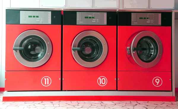 Three red washing machines in coin laundry — Stock Photo, Image